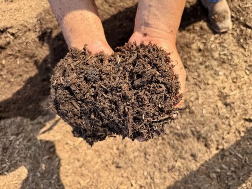 Texas Garden Materials installing premium hardwood brown mulch in Houston flower beds and landscapes, bulk delivery and professional installation available.
